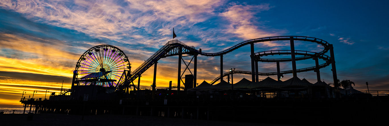 Roller coaster and ferris wheel at sunset